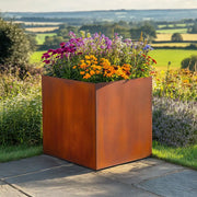 Corten metal planter with flowers in a garden setting